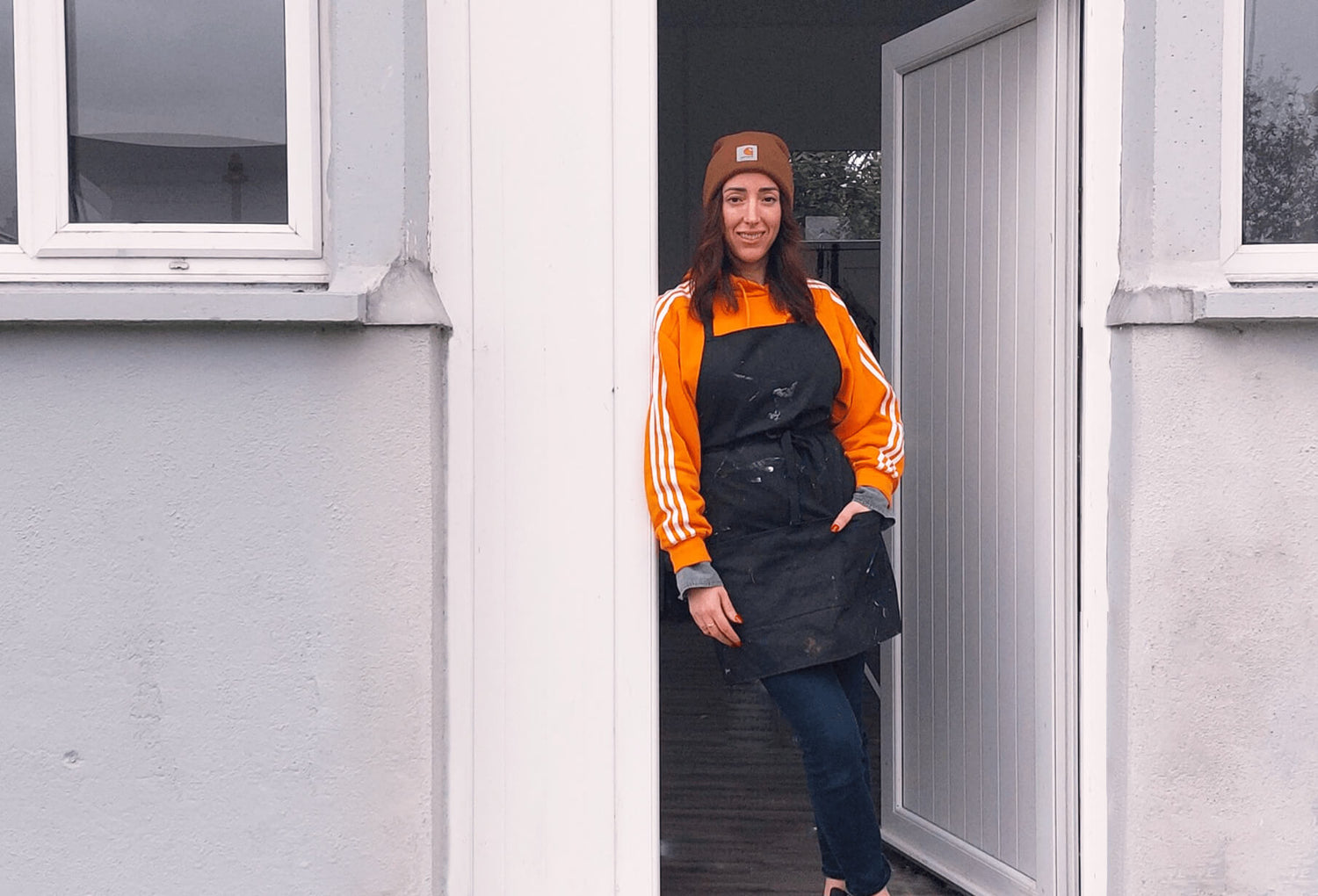Irish artist Bridie Keogh wearing  a black apron standing outside her art studio 