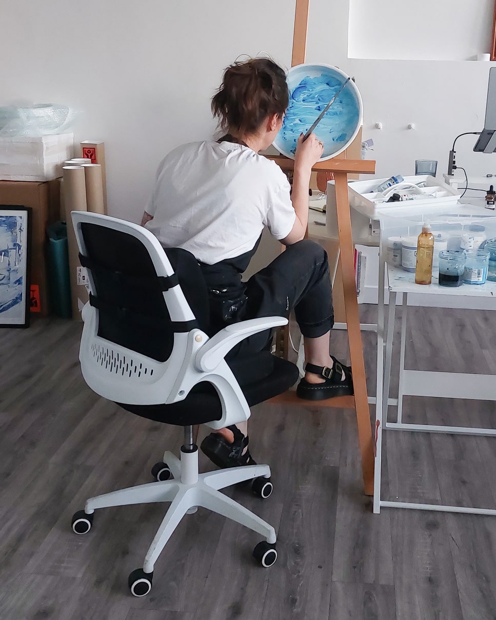 Irish artist Bridie Keogh working in  her art studio, wearing a white shirt and black pants. 
